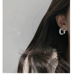 Close-up of minimalist 925 silver C-shape earring with brushed and polished textures