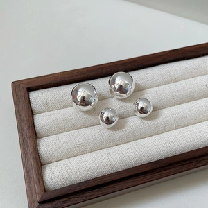 Polished S925 sterling silver sphere stud earrings in small and large sizes on a tray