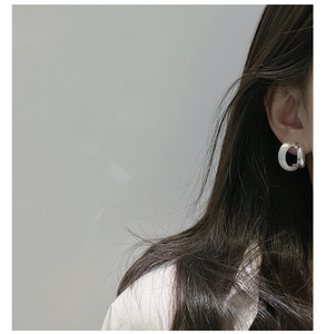 Macro side view of silver brushed matte chunky hoop earrings worn by a model