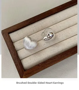 Detailed close-up of double-sided heart earrings with brushed and polished silver finish