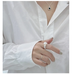 Detail of S925 silver pearl croissant ring set and heart necklace worn on a white shirt