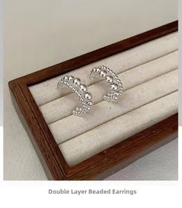 Detail of S925 sterling silver double-layered beaded earrings on jewelry display tray