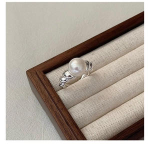 Macro shot of S925 silver pearl ring with spiral texture in a linen jewelry box