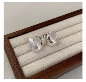 Macro view of S925 sterling silver hoop earrings with brushed and polished textures