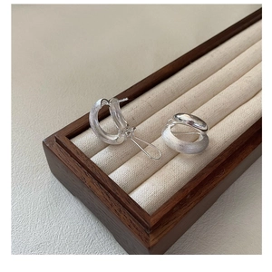 Macro detail of 925 sterling silver C-shape earrings with brushed and polished texture