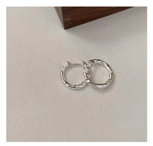 Macro detail of S925 silver huggie earrings with a unique molten lava texture design