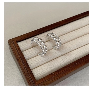 Macro view of C-shaped double-layered silver beaded earrings on jewelry display