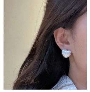 Close-up of S925 silver heart earring with pearl white texture on a female model
