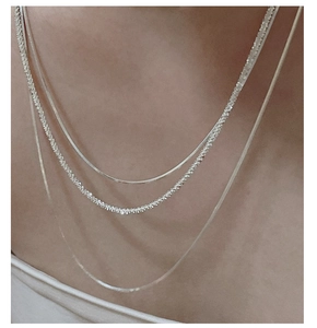 Close-up of triple-layered S925 silver necklace featuring sleek snake chains and shimmering links