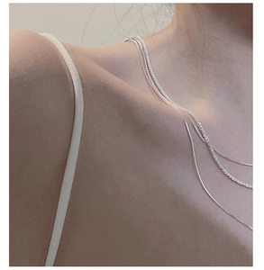 Close-up of layered S925 silver square snake chain necklace on neck and shoulder