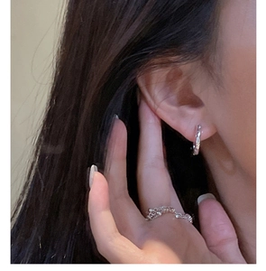 Macro detail of silver twisted texture earrings and matching ring on female model