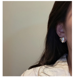 Close-up of polished S925 sterling silver heart earrings worn by a model in natural light