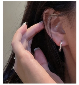 Detail of S925 sterling silver hoop earrings with irregular hammered texture on model