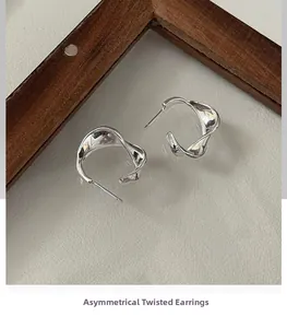 Close-up of silver wavy earrings with modern irregular twisted geometric metal texture