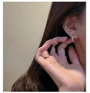 Close-up of minimalist S925 sterling silver textured hoop earring and twisted band ring