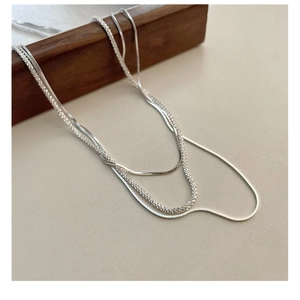 Close-up of dual-layer S925 silver snake chain and shimmering textured necklace design