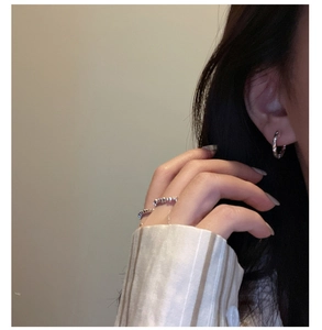 Detail of S925 sterling silver hoop earrings and textured rings worn by a model