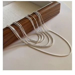 Macro shot of S925 sterling silver multi-layer snake bone and shimmering link necklaces