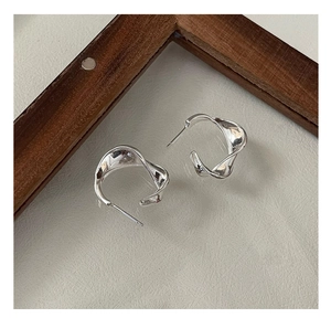 Detail view of twisted C-shaped earrings with wave texture and polished silver finish