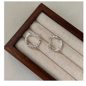 Close-up of S925 silver hoop earrings with irregular hammered texture on jewelry tray