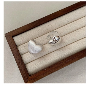 Close-up of S925 silver heart earrings with brushed and polished texture contrast