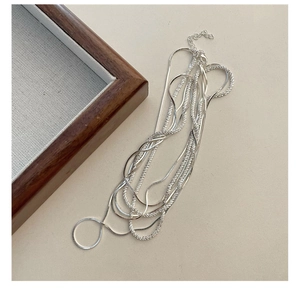 Detail of multi-layer S925 sterling silver snake bone chain necklace on beige background