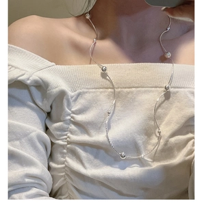 Detail of minimalist S925 sterling silver beaded layering necklace on a model