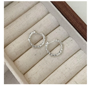 Macro detail of silver hammered texture earrings displayed on a soft beige jewelry tray
