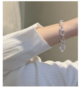 Dettaglio di un bracciale in argento sterling S925 testurizzato con ciondolo a cuore al polso