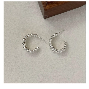 Detail of S925 sterling silver C-shaped earrings with minimalist beaded design on leather