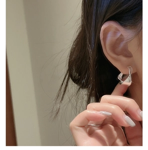 Detail of S925 sterling silver hoop earring featuring a stylish twisted wave design on model