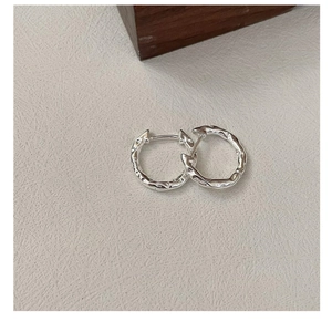 Macro shot of S925 silver hoop earrings featuring irregular lava texture and modern design
