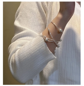 Detail of silver S925 multilayer beaded bracelet with star charm on model's wrist
