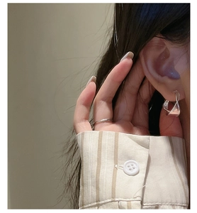 Detail of elegant S925 sterling silver wave earrings and ring worn by a model