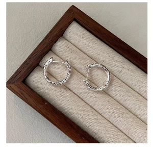Macro detail of S925 sterling silver hoop earrings with irregular hammered texture finish