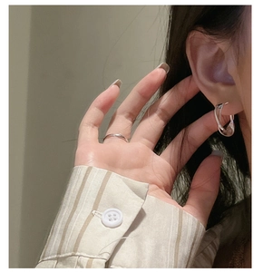 Close-up of S925 sterling silver twisted hoop earrings and minimalist ring worn by model
