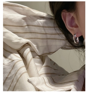 Close-up of S925 sterling silver hoop earrings with a modern twisted texture worn by a model