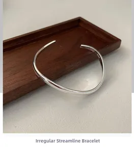Detailed view of S925 sterling silver stamp on minimalist wavy open cuff bracelet
