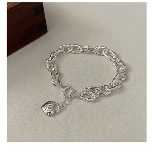 Dettaglio macro del ciondolo a cuore martellato su bracciale a catena S925 martellata