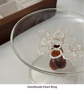 Detail of handmade freshwater pearl rings with silver beads on a glass stand