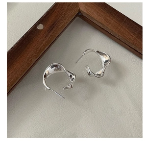 Detailed view of polished S925 sterling silver hoop earrings with a twisted wave design