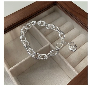 Dettaglio macro del bracciale a catena spessa argentata con ciondolo a cuore testurizzato