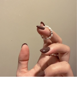 Close-up of handmade freshwater pearl elastic ring with a silver bead on a model's finger