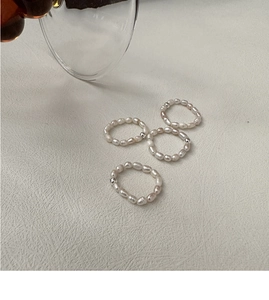 Detail of four handmade elastic freshwater pearl rings with small silver metal beads