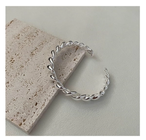 Gros plan d'un bracelet jonc torsadé en argent S925 sur une texture de pierre