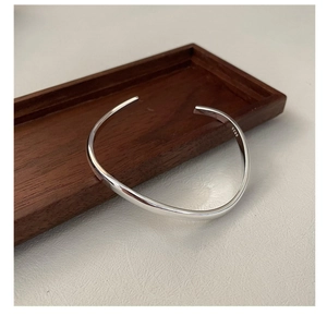 Detailed close-up of polished S925 sterling silver bangle with wavy minimalist design