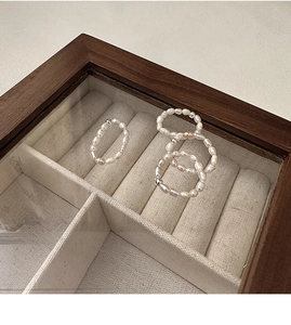 Detail shot of four elastic freshwater pearl rings with silver beads in a jewelry box
