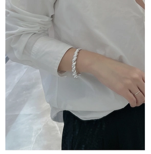 Détail macro d'un bracelet torsadé en argent 925 et d'une bague polie sur un modèle