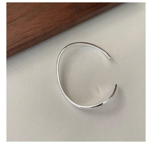 Detailed close-up of polished S925 sterling silver minimalist wavy open cuff bracelet