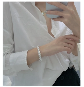 Gros plan d'un bracelet jonc torsadé en argent montrant la texture métallique au poignet